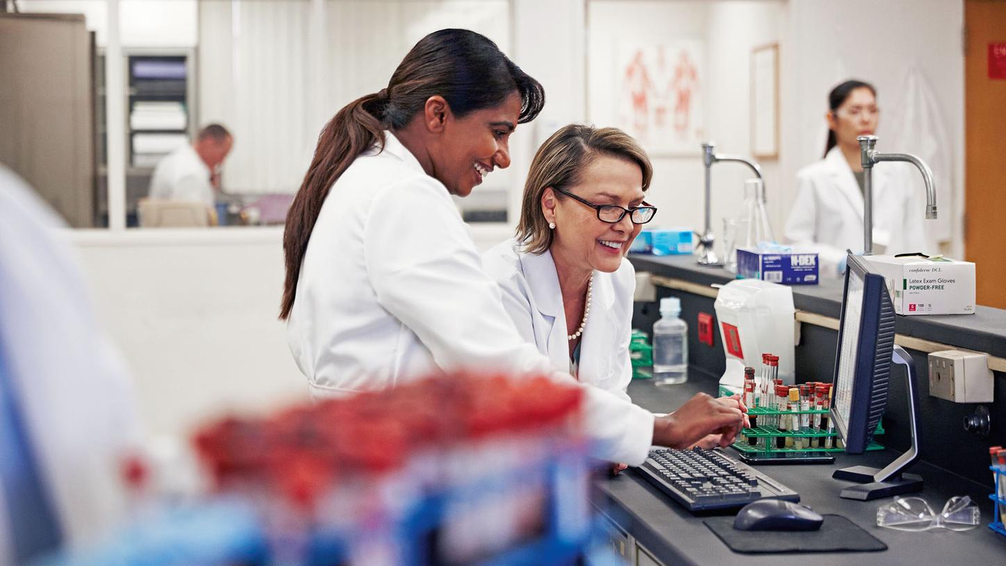 Laboratory colleagues reviewing work at a specimen workstation
